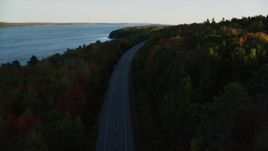 5.5K aerial stock footage flying over road with no traffic, colorful forest in autumn, Stockton Springs, Maine, sunset Aerial Stock Footage | AX149_121