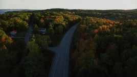 5.5K aerial stock footage flying over road and tilt down, light traffic, colorful forest in autumn, Stockton Springs, Maine, sunset Aerial Stock Footage | AX149_123