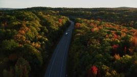 5.5K aerial stock footage flying over forest road with light traffic, fall foliage, in autumn, Stockton Springs, Maine, sunset Aerial Stock Footage | AX149_124