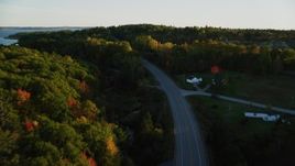 5.5K aerial stock footage flying high over quiet road among colorful forest, autumn, Stockton Springs, Maine, sunset Aerial Stock Footage | AX149_125