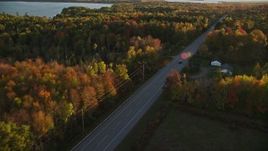 5.5K aerial stock footage tracking car on road through forest in autumn, Stockton Springs, Maine, sunset Aerial Stock Footage | AX149_130E