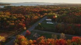 5.5K aerial stock footage tracking a car on road passing by small town, autumn, Stockton Springs, Maine, sunset Aerial Stock Footage | AX149_144E