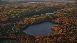 5.5K aerial stock footage flying by McClure Pond, Cain Pond, forest in autumn, Searsport, Maine, sunset Aerial Stock Footage | AX149_152E