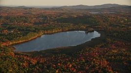 5.5K aerial stock footage flying by Cross Pond, forest in autumn, Belmont, Maine, sunset Aerial Stock Footage | AX149_167