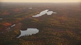 5.5K aerial stock footage flying by James Pond and Long Pond, forest in autumn, Palermo, Maine, sunset Aerial Stock Footage | AX149_200E