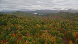 5.5K aerial stock footage flying over dense forest in autumn, approach Cezar Lake, overcast, Lovell, Maine Aerial Stock Footage | AX150_133E