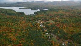 5.5K aerial stock footage flying over forest, approach Cezar Lake, tilt down on rural homes, autumn, overcast, Lovell, Maine Aerial Stock Footage | AX150_137