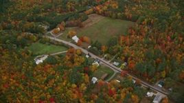 5.5K aerial stock footage flying over forest, approach Cezar Lake, tilt down on rural homes, autumn, overcast, Lovell, Maine Aerial Stock Footage | AX150_137E