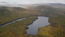 5.5K aerial stock footage flying by Horseshoe Pond, dense forest, hills, autumn, overcast, Lovell, Maine Aerial Stock Footage | AX150_143E