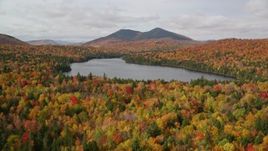 5.5K aerial stock footage flying over autumn forest, descend and fly over Mountain Pond, White Mountains, New Hampshire Aerial Stock Footage | AX150_153E