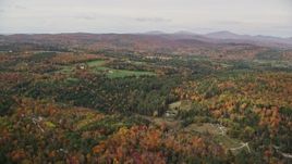 5.5K aerial stock footage flying over colorful forest, approaching small farms, autumn, Ryegate, Vermont Aerial Stock Footage | AX150_312E