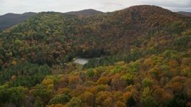 5.5K aerial stock footage tilting down over pond, brightly colored forested hills in autumn, Sharon, Vermont Aerial Stock Footage | AX150_458