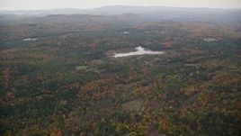 5.5K aerial stock footage flying over forested hills, approaching pond, overcast, autumn, Croydon, New Hampshire Aerial Stock Footage | AX151_071E