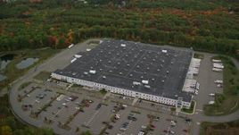 5.5K aerial stock footage flying by warehouse building, forest in autumn, Londonderry, New Hampshire Aerial Stock Footage | AX152_051E