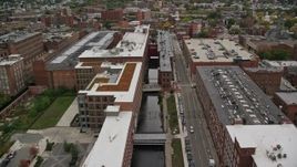 5.5K aerial stock footage flying over factory buildings along a canal, autumn, Lowell, Massachusetts Aerial Stock Footage | AX152_137E