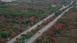 5.5K aerial stock footage flying over interstate with traffic towards trees with fall foliage, Norwood, Massachusetts Aerial Stock Footage | AX152_235