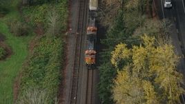5.5K aerial stock footage of a reverse view tracking a train in Columbia River Gorge, reveal trucks on country road in Oregon Aerial Stock Footage | AX153_183