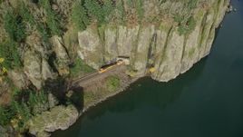 5.5K aerial stock footage revealing train tracks and a train emerging from the cliffs of Columbia River Gorge, Washington Aerial Stock Footage | AX154_012E