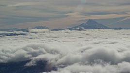5.5K aerial stock footage of Mount Jefferson and the Three Sisters Volcanoes seen from across low clouds, Cascade Range, Oregon Aerial Stock Footage | AX154_098E