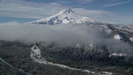 5.5K aerial stock footage of low clouds over forest and ridge near snow-capped Mount Hood, Cascade Range, Oregon Aerial Stock Footage | AX154_121