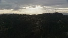 5.5K aerial stock footage of homes and trees on a hillside, with godrays through clouds in the background, Southwest Portland, Oregon Aerial Stock Footage | AX155_092