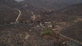 5K aerial stock footage flyby fire-ravaged rural homes surrounded by wildfire damage in the Santa Monica Mountains, California Aerial Stock Footage | AX42_014E