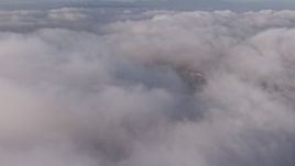 4K aerial stock footage flying over a dense marine layer with a break in the clouds, Los Angeles, California Aerial Stock Footage | AX43_052