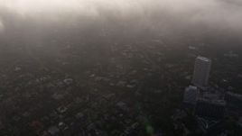 4K aerial stock footage flying over the edge of marine layer clouds and tilt down to Los Angeles below, California Aerial Stock Footage | AX43_056