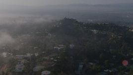 4K aerial stock footage flying over marine layer to approach upscale, hillside homes near a radio tower, Beverly Hills, California Aerial Stock Footage | AX43_059