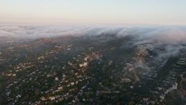 4K aerial stock footage of Hillside homes with fog rolling over the tops of hills, Sherman Oaks, California, sunset Aerial Stock Footage | AX44_004