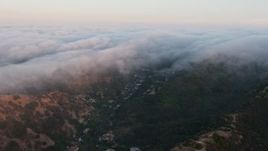 4K aerial stock footage of a marine layer pouring over the hills, Studio City, California, sunset Aerial Stock Footage | AX44_006