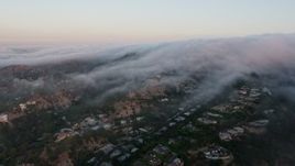 4K aerial stock footage of a marine layer rolling over the hills and homes, Studio City, California, sunset Aerial Stock Footage | AX44_013