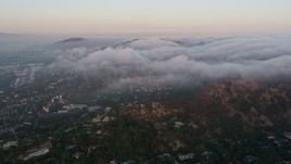 4K aerial stock footage flying over homes with marine layer flowing over hills, Studio City, California, sunset Aerial Stock Footage | AX44_014