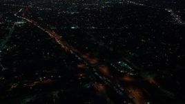 4K aerial stock footage orbiting a highway with medium traffic among city light, Echo Park, Los Angeles, night Aerial Stock Footage | AX44_087