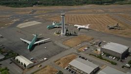 5K aerial stock footage of three airliners parked around an airport control tower, seen while descending, Paine Field, Washington Aerial Stock Footage | AX45_155E