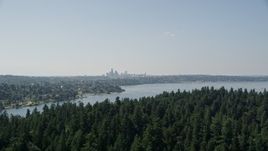5K aerial stock footage fly over tree covered Bailey Peninsula to reveal Downtown Seattle skyline, Washington Aerial Stock Footage | AX47_005