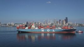 5K aerial stock footage flyby a cargo ship and tugboat sailing Elliott Bay to focus on the Downtown Seattle skyline, Washington Aerial Stock Footage | AX47_030