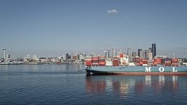 5K aerial stock footage flyby a cargo ship and tugboat sailing Elliott Bay to focus on the Downtown Seattle skyline, Washington Aerial Stock Footage | AX47_030E