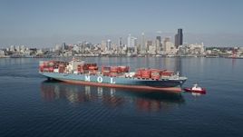 5K aerial stock footage flyby a cargo ship and tugboat with the Downtown Seattle skyline in the background, Washington Aerial Stock Footage | AX47_035