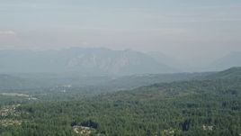 5K aerial stock footage of a view of the distant Cascade Range in Washington, seen from evergreen forest Aerial Stock Footage | AX48_023