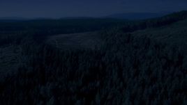 4K day for night color corrected aerial stock footage of evergreens and pan across forest and clear cut areas, King County, Washington Aerial Stock Footage | AX48_094_DFN
