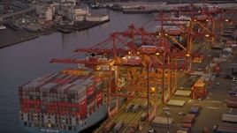 5K aerial stock footage of passing Harbor Island to approach a fully-laden cargo ship docked at the Port of Seattle, Washington, sunset Aerial Stock Footage | AX50_067