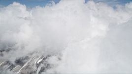 5K aerial stock footage orbit Mount St. Helens with snowy slopes peeking through thick cloud coverage, Washington Aerial Stock Footage | AX52_058