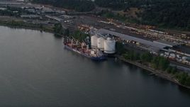 5K aerial stock footage approach oil tanker beside a silo and train yard, Willamette River, North Portland, Oregon, sunset Aerial Stock Footage | AX54_027