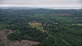 5K aerial stock footage of a farm field beside a country road, evergreen forest, and clear cut areas in Clatsop County, Oregon Aerial Stock Footage | AX56_062