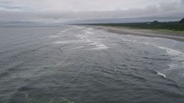 5K aerial stock footage of low altitude flight over ocean waves near an empty beach in Ilwaco, Washington Aerial Stock Footage | AX56_120E