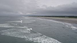 5K aerial stock footage of ocean waves rolling toward a beach with a few people on the shore in Long Beach, Washington Aerial Stock Footage | AX56_136E