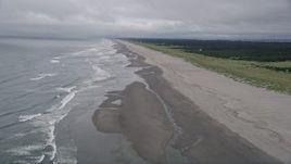 5K aerial stock footage fly over ocean waves and a lone person walking the beach in Oceanside, Washington Aerial Stock Footage | AX56_143