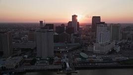 5K aerial stock footage pass riverfront hotels and skyscrapers in Downtown New Orleans with the setting sun in the background, Louisiana Aerial Stock Footage | AX61_064