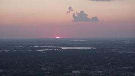 5K aerial stock footage of the setting sun dipping below the horizon beyond the Mississippi River and Carrollton, Louisiana Aerial Stock Footage | AX61_078